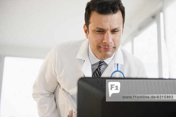 Mixed race doctor looking at computer monitor