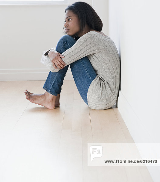 Barefoot mixed race woman sitting on floor