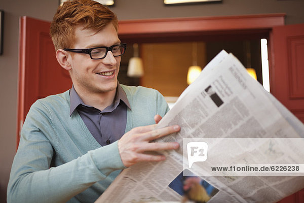 Ein Mann  der eine Zeitung in einem Restaurant liest.