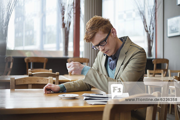 Ein Mann trinkt Tee und liest eine Zeitung in einem Restaurant.