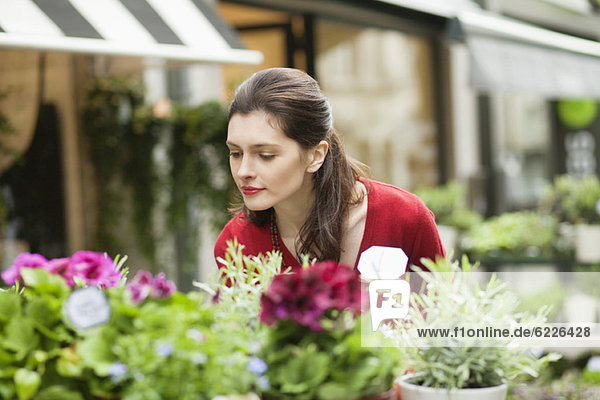 Frau riecht Blumen in einem Blumenladen