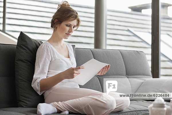 Woman sitting on a couch and reading a document