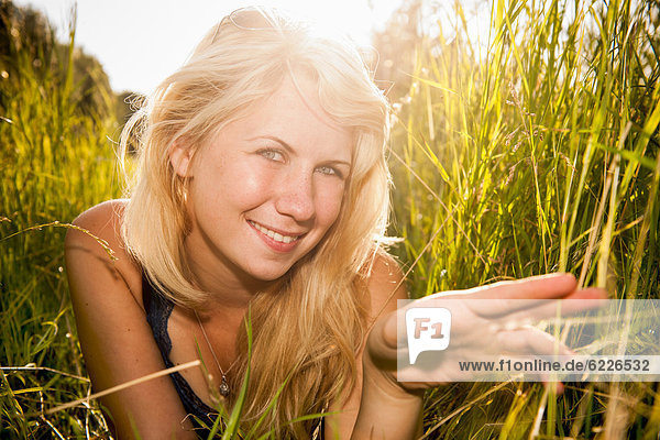 Junge Frau liegt im hohen Gras