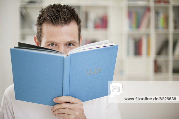 Portrait of a holding a book in front of his face