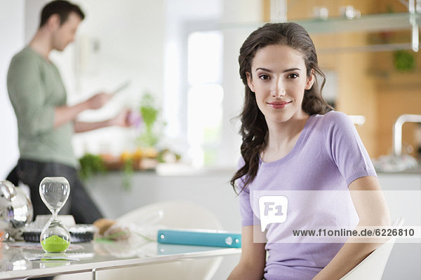 Frau lächelt mit ihrem Mann bei der Zubereitung des Essens im Hintergrund