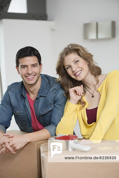 Couple leaning over cardboard boxes and smiling