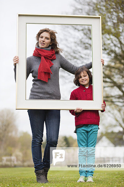 Woman and her son holding a picture frame in a park