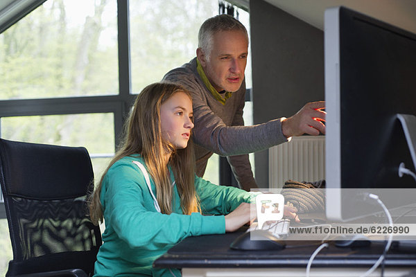 Girl using a computer with her father at home