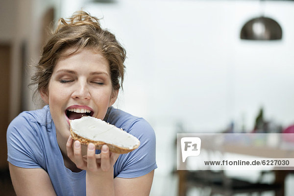 Woman eating toast with cream spread on it