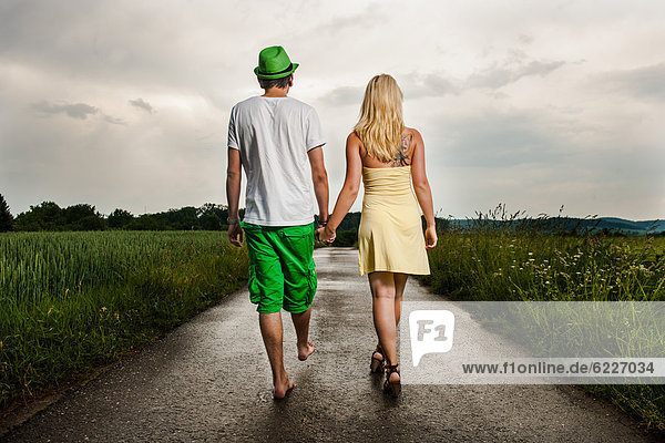 Young couple walking hand in hand in rural landscape