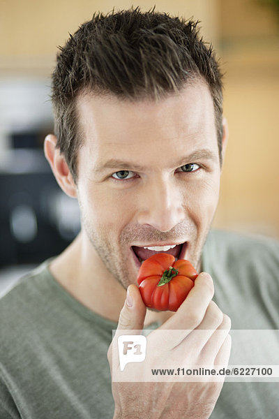 Mann  der eine Tomate isst