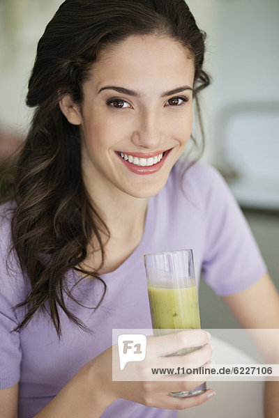Frau hält ein Glas kalte Suppe und lächelt