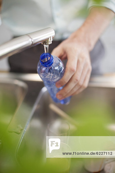 Man filling a bottle with water in the kitchen
