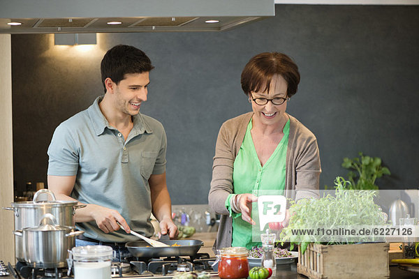 Frau hilft ihrem Sohn beim Kochen in der Küche