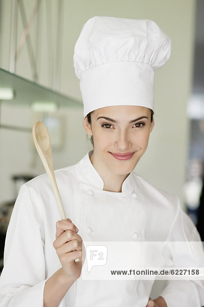 Happy female chef holding a wooden spoon