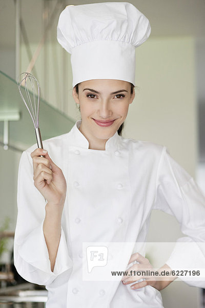 Happy female chef holding a wire whisk