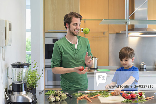 Mann und Sohn schneiden Gemüse in der Küche