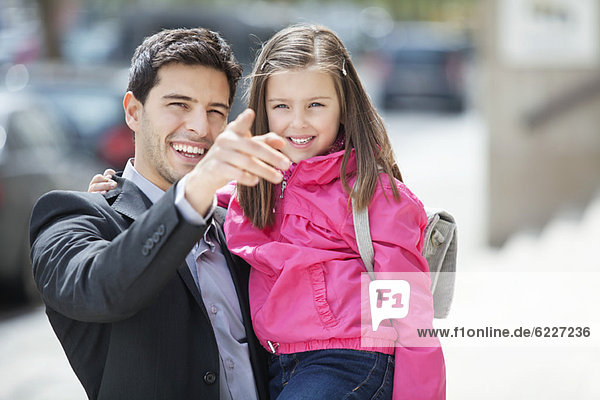 Man carrying his daughter and pointing with finger