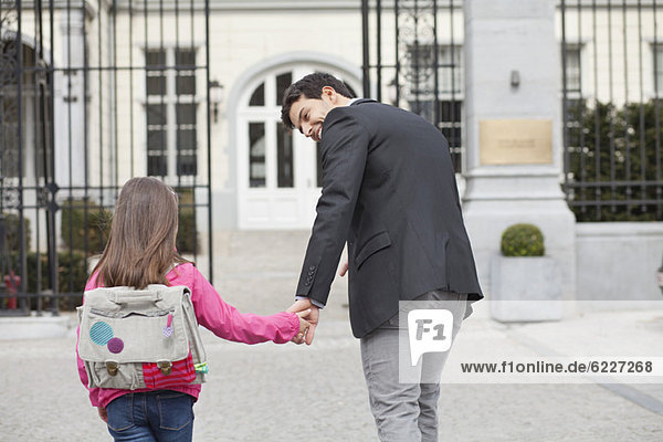 Girl walking towards school with her father