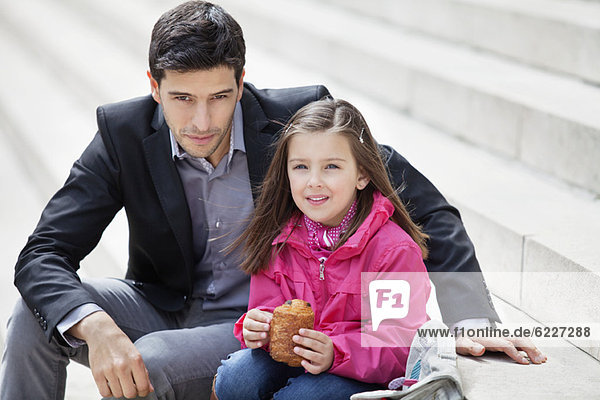 Mann sitzend mit seiner Tochter beim Essen von Schmerz au chocolat