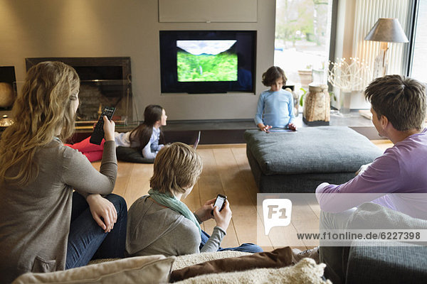 Family using electronic gadgets in a living room