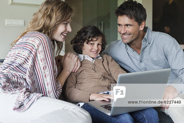 Junge mit Laptop bei seinen Eltern zu Hause