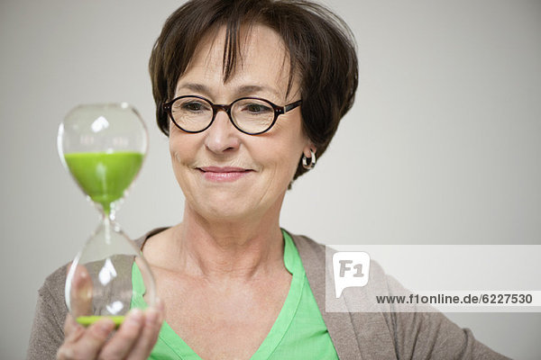 Woman looking at an hourglass and smiling