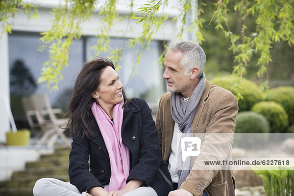 Romantisches Paar im Garten sitzend und lächelnd