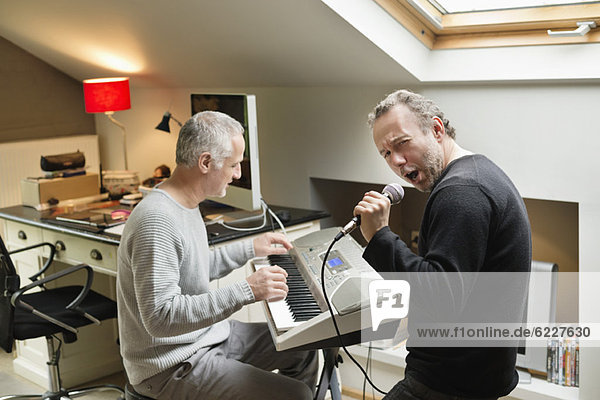 Two male friends playing a piano and singing