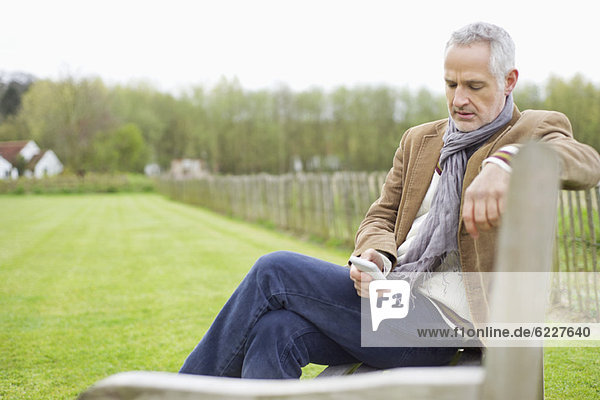 Man text messaging on a mobile phone in a field