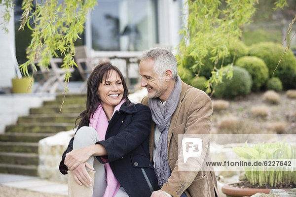 Romantic couple sitting in a garden and smiling