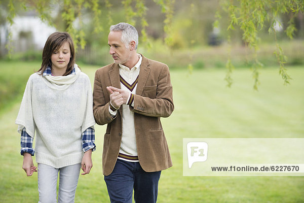 Mann diskutiert mit seiner Tochter beim Spaziergang im Park