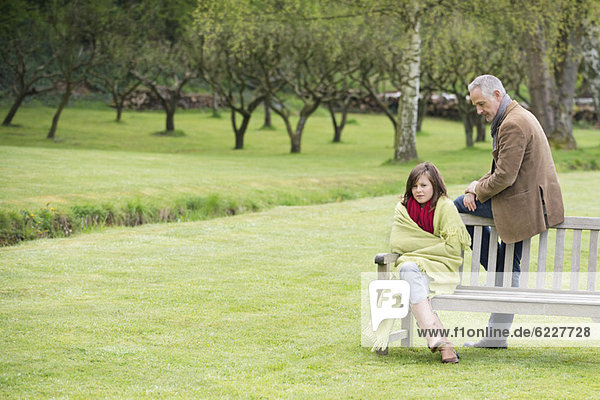 Man sitting with his daughter on a bench in a park
