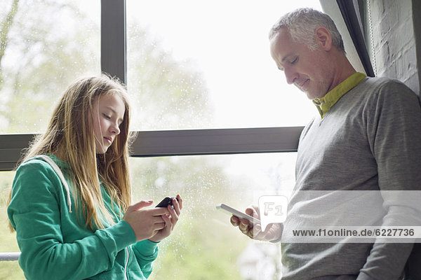 Mann und Tochter benutzen ihre Handys