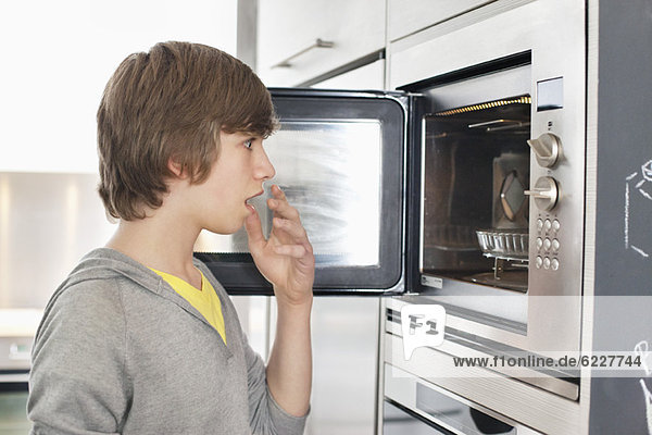 Teenager-Junge schaut in einen Ofen mit Überraschung