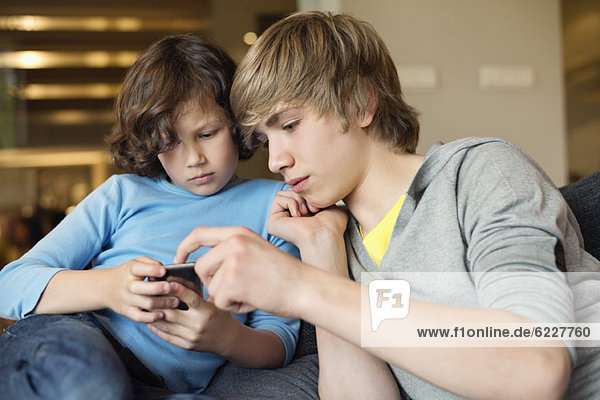 Teenage boy with his brother using a cellphone