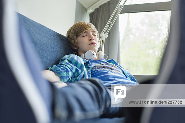 Teenager-Junge schläft auf einer Couch mit Kopfhörer