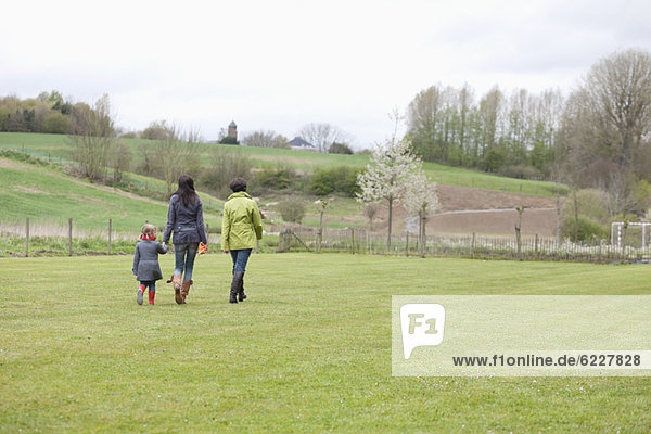 Mädchen  das mit ihrer Mutter und Großmutter auf dem Rasen spazieren geht.