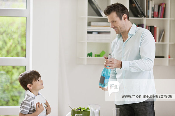 Mann zeigt seinem Sohn eine Sprudelwasserflasche