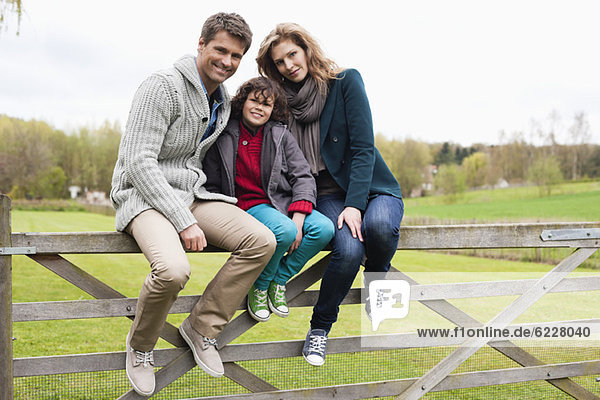 Junge sitzend mit seinen Eltern am Tor einer Hütte