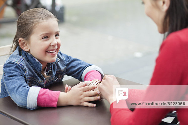 Girl sitting with her mother at a sidewalk cafe