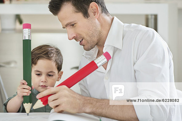 Man and son writing with big pencils