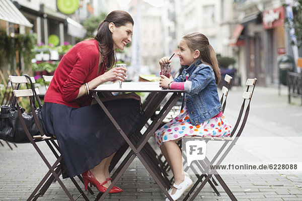 Woman and her daughter drinking at a sidewalk cafe