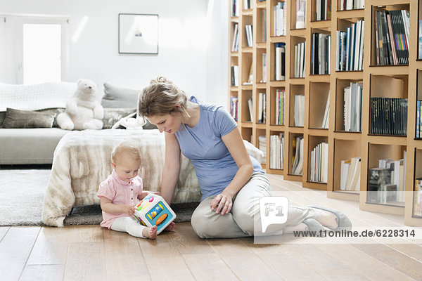 Woman sitting near her daughter playing with a toy