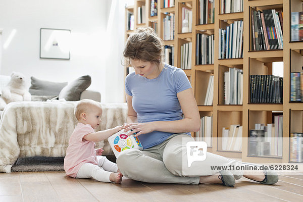 Woman sitting near her daughter playing with a toy