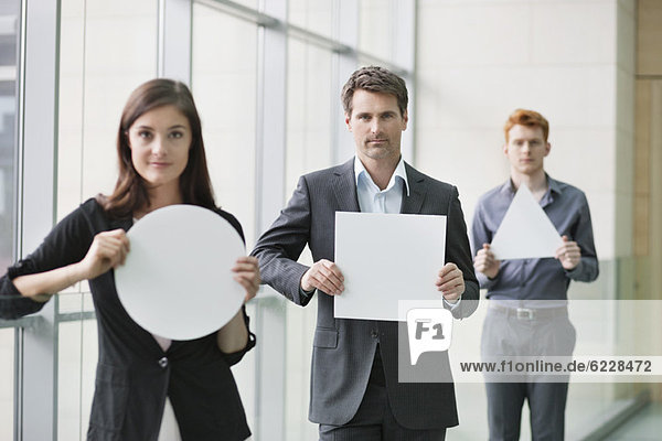 Business executives holding blank placards in an office