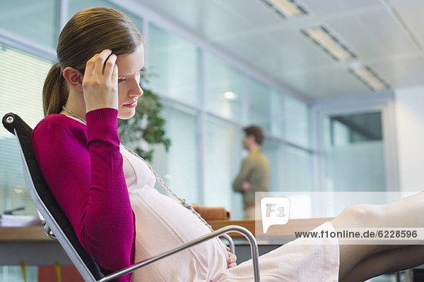 Schwangere im Büro sitzend