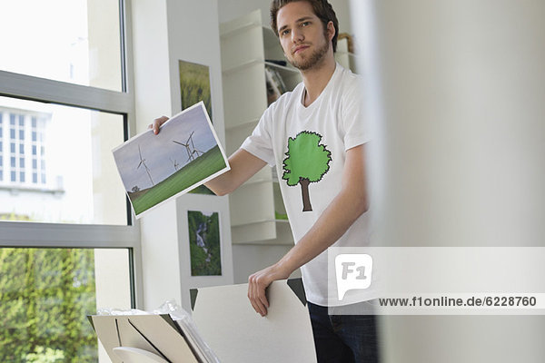 Mann hält ein ökologisches Plakat mit einer Windkraftanlage.