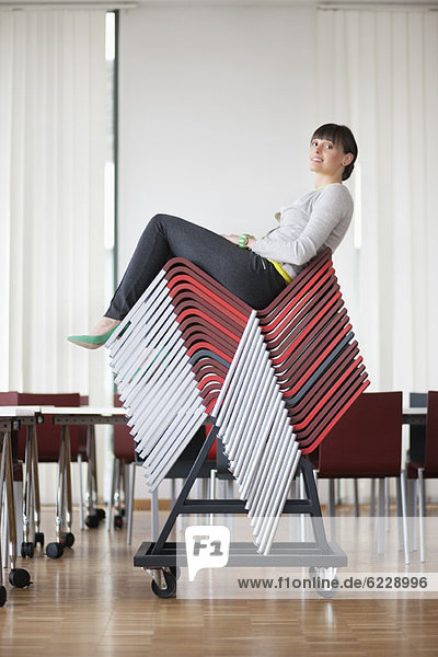 Businesswoman sitting on pileup chairs in an office