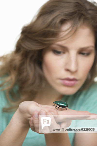 Frau schaut auf einen Käfer an der Hand